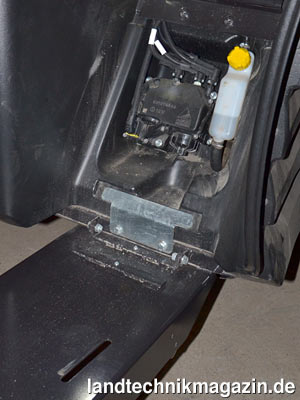 Bild 21: Für das Hydrauliköl gibt es bei der neuen Valtra T-Serie hinter  dem Kabinenaufstieg eine Not-Einfüllöffnung (gelber Schraubverschluss).  Über einen Schlitz in der Abdeckung (unten, linke Bildhälfte) kann der  Hydraulikölstand kontrolliert