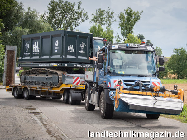 lDer wasserstoffbetriebene Mercedes-Benz Unimog Geräteträger U 430 mit Schmidt Frontanbaukehrmaschine transportierte die ebenfalls wasserstoffbetriebene Mörtelbauer Muldenkipper-Raupe zur Präsentation in Fürstenzell.